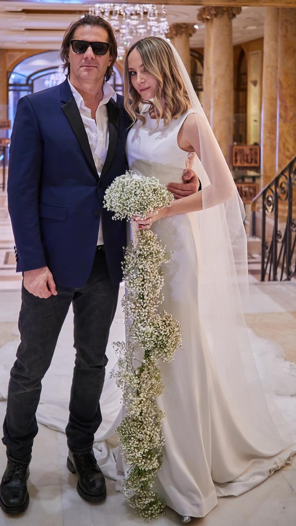 octavia geamanu in rochie de mireasa tinand un buchet de flori albe in mana langa sotul ei marian ionescu