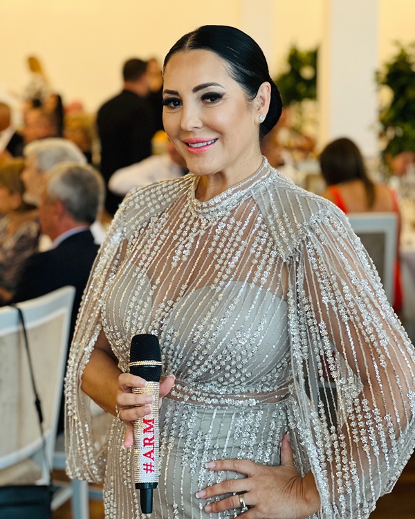 angeka rusu imbracata in rochie alba cu microfonul in mana