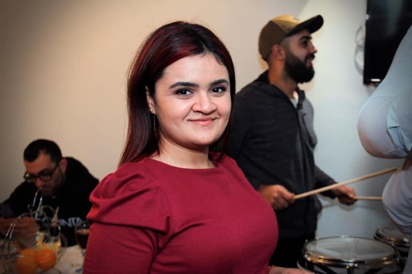 femeie bruneta cu parul lung si drept imbracata in rochie grena