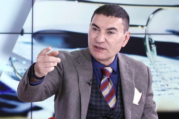 cristi borcea in costum gri arata cu degetul intr-un platou tv