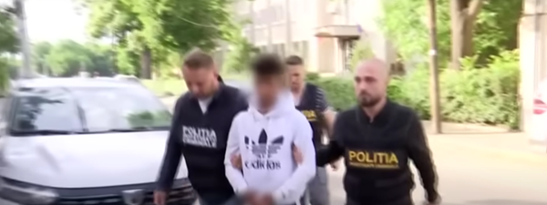 un tanar in hanorac alb cu catuse intre doi politisti