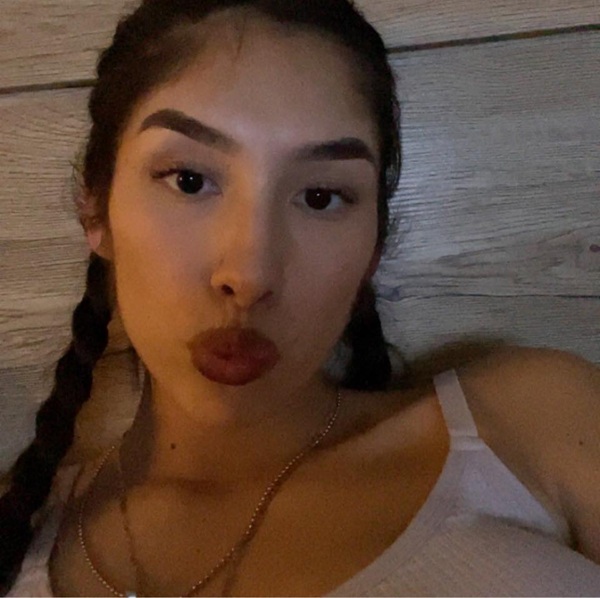 femeie bruneta cu parul prins in cozi in maieu alb face un selfie