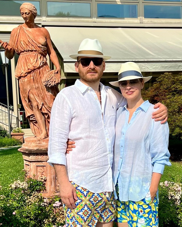 andreea marin cu palarie de soare si ochelari la ochi imbracata in culori deschise langa adrian brîncoveanu