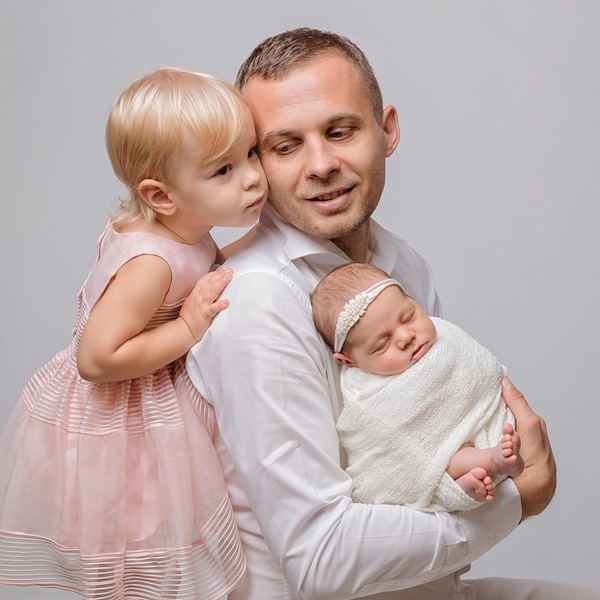 caius lungu isi tine in brate bebelusa si in spatele lui este o fetita imbracata in roz