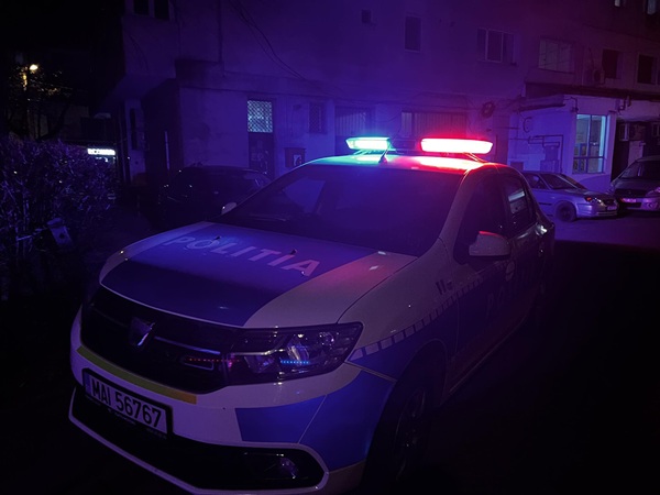 o masina de politie trasa la un bloc cu girofarele pornite pe timp de noapte