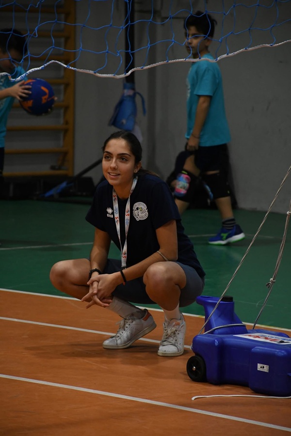 fata imbracata in sportiva sta pe teren in interior si zambeste