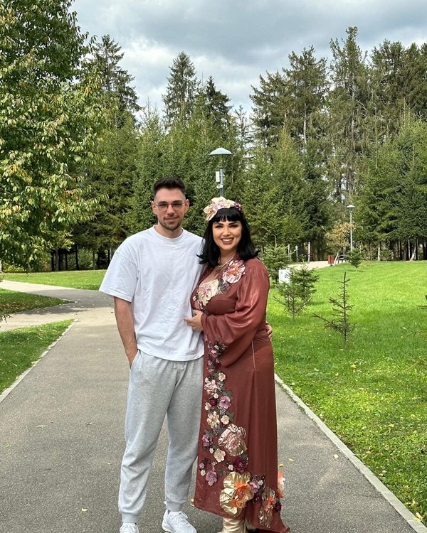 ozana barabancea in rochie inflorata cu fiul ei pe o alee in parc imbracat in tricou alb