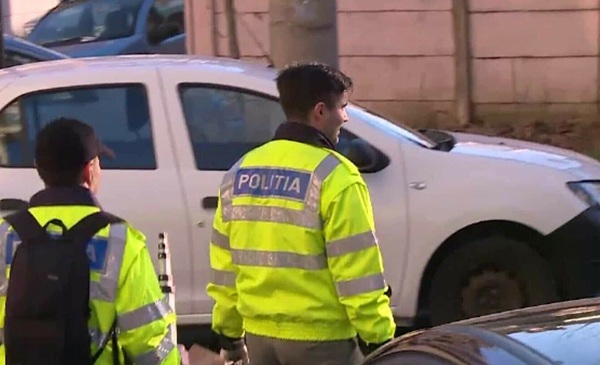 doi politisti imbracati cu veste reflectorizante langa masina de politie