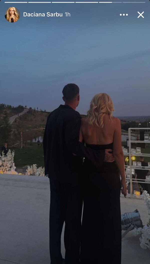 daciana sarbu in rochie lunga neagra este tinuta de mijloc de un tanar imbracat in negru