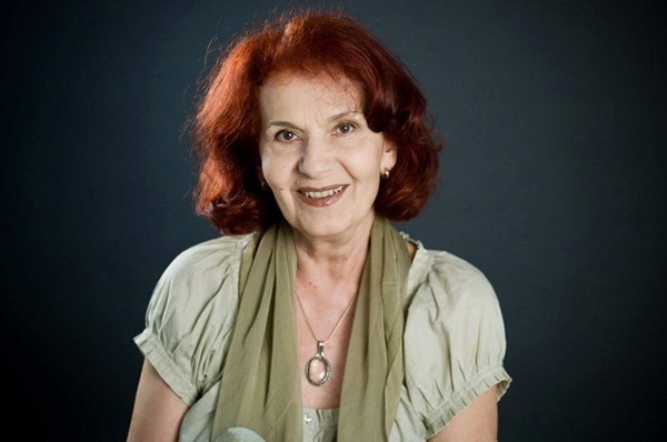 iarina demian cu o bluza cu maneca scurta vernil si o esarfa la gat priveste la camera