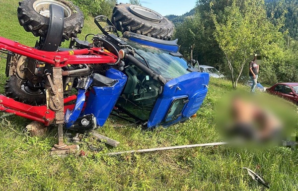 tractor rasturnat pe un deal cu persoane langa si un barbat prins sub el