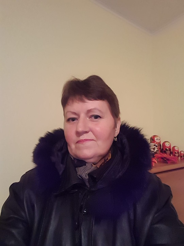femeie tunsa scurt imbracata in geaca cu gluga de blana sta pe canapea