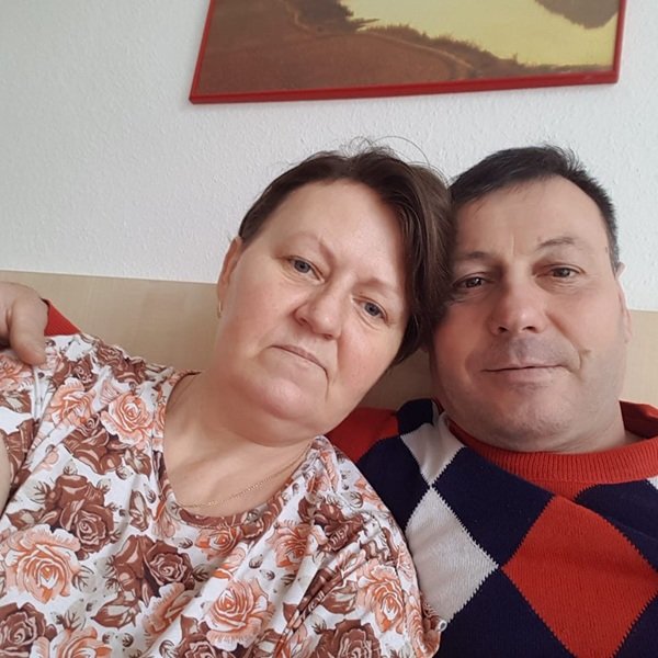 barbat imbracat in pulover cu carouri sta langa o femeie in bluza roz pe o canapea
