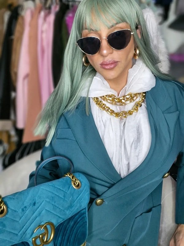 femeie cu parul lung albastru in costum albastru cu ochelari de soare la ochi