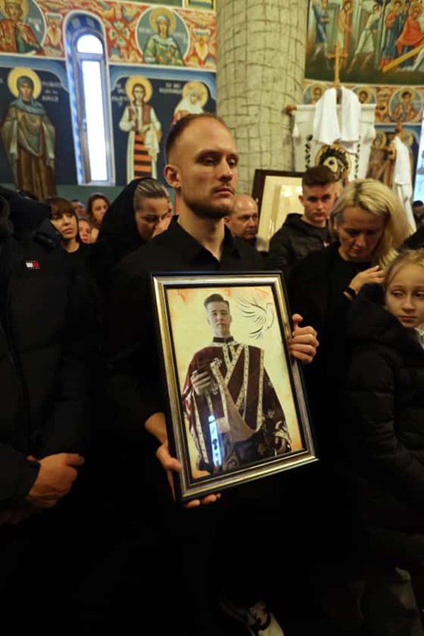 un barbat tine in mana fotografia unui viitor preot la inmormantare