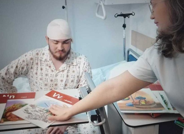 pacient cu bandaj la cap priveste imagini pe o carte