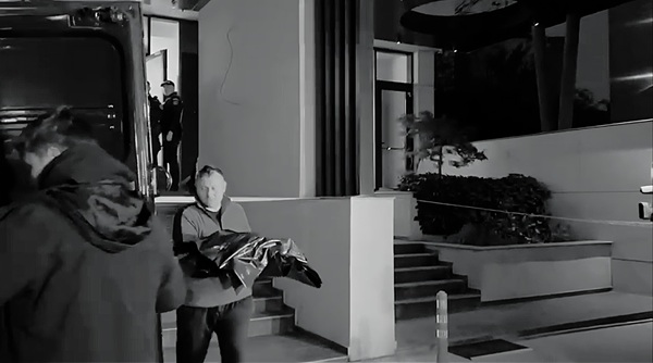 un barbat cara pe brate trupul unei fetite intr-un sac negru