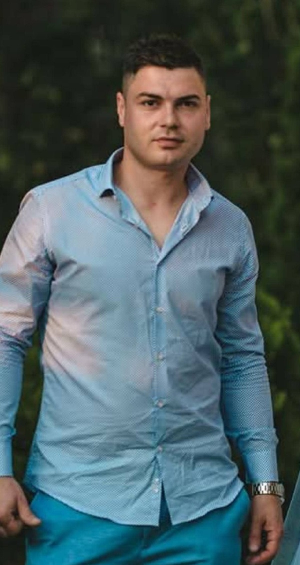 barbat inalt imbracat in camasa albastra si blugi albastri