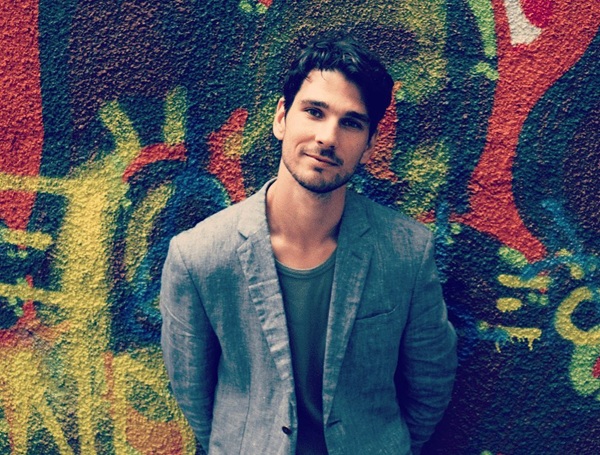 anghel damian in costum gri in fata unui perete colorat