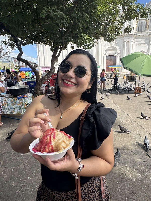 femeie imbracata in negru cu ochelari de soare la ochi mananca inghetata