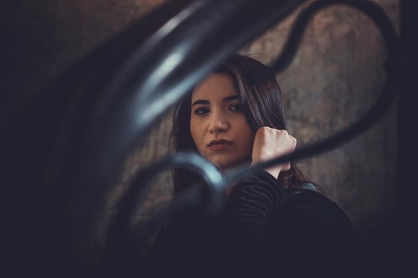 malina guler cu parul brunet desprins priveste in camere dupa bare de fier