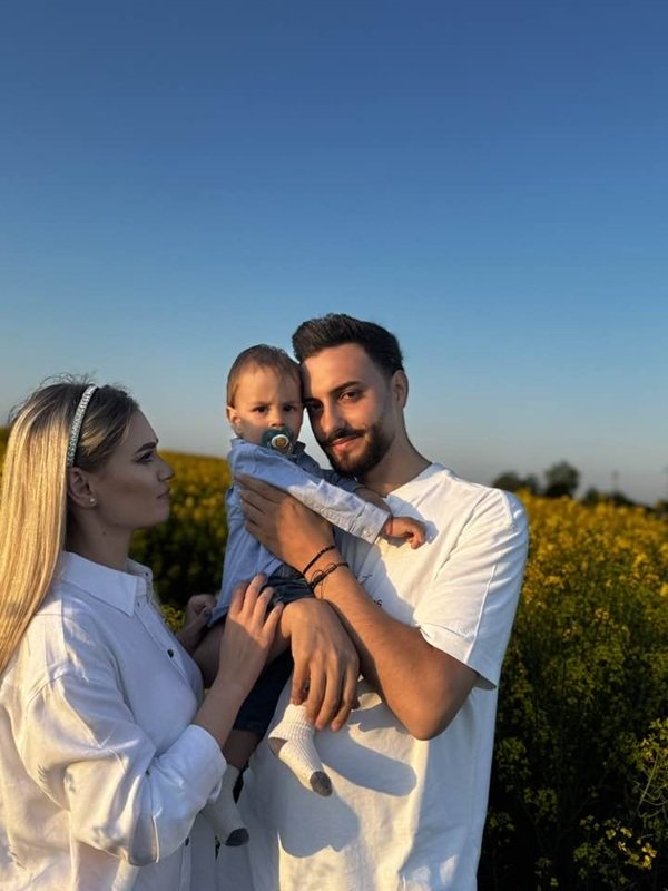 barbat si femeie imbracati in alb isi tin copilul in brate