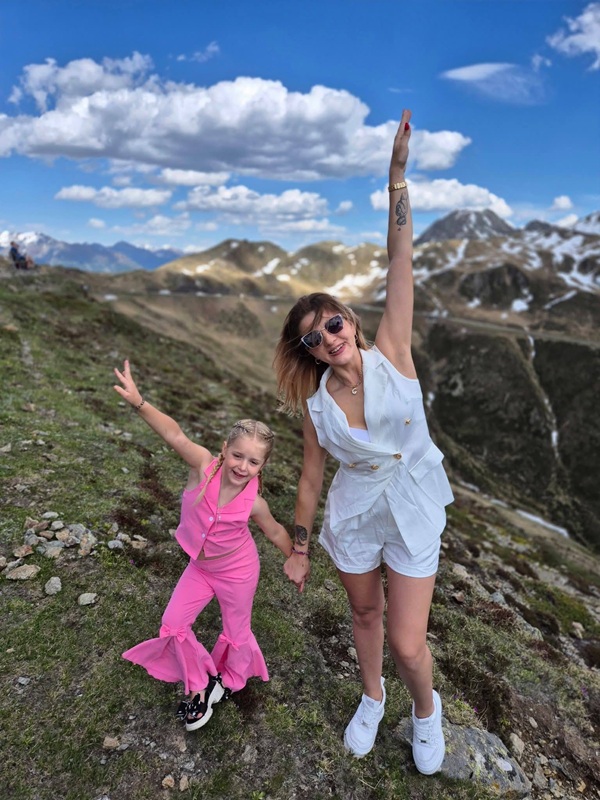 femeie in compleu alb si fetita ei imbracata in roz pe munte