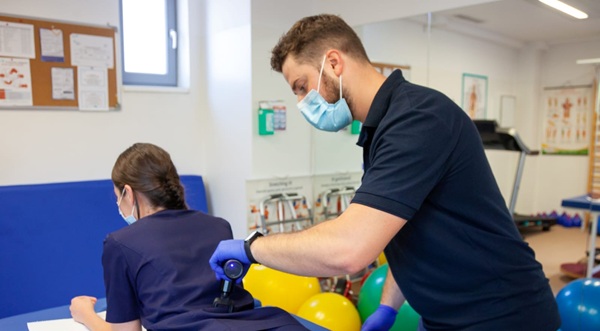 kinetoterapeut imbracat in negru are grija de o pacienta