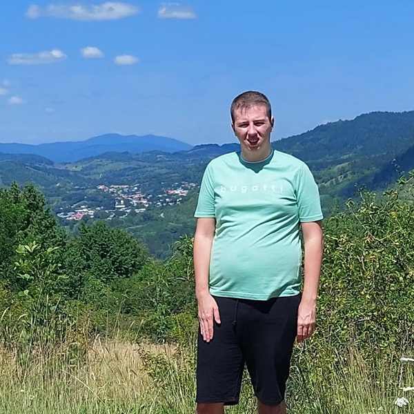 baiat imbracat in tricou bleu si pantaloni negri pe un deal