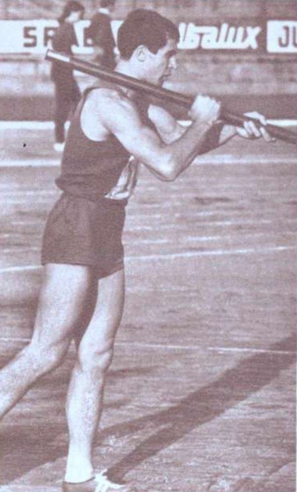 fotografie alb negru cu dinu pistalu imbracat in costum negru cu prajina in mana pe teren