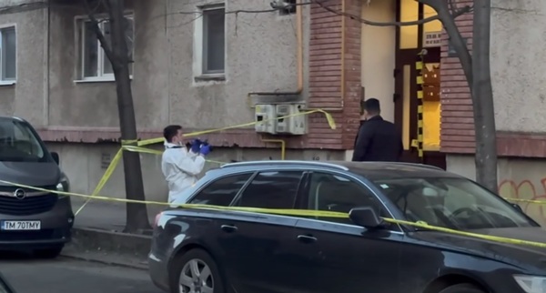 un angajat de la criminalistica imbracat in alb face poze la o scara de bloc intr-un perimetru inconjurat de banda galbena