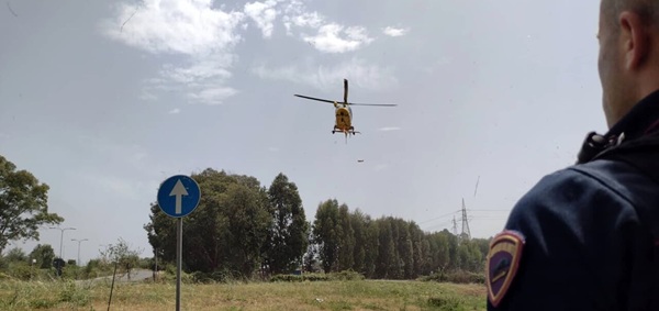 politist aflat pe un camp se uita spre un elicopter care se pregateste sa aterizeze