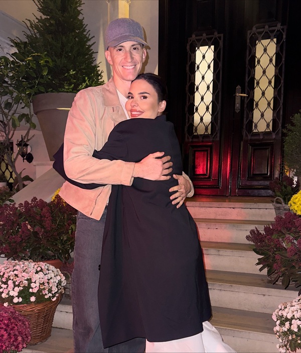 andreea popescu in palton negru lung si pantaloni albi isi tine fostul sot in brate imbracat in crem