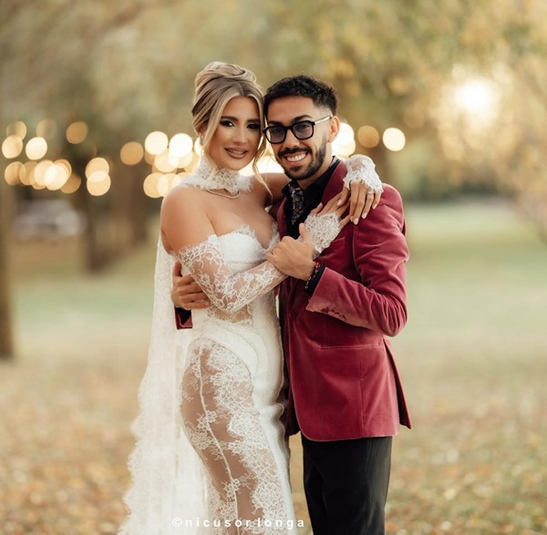 armin nicoara in sacou rosu si claudia puican in rochie alba cu parul prins in coc se tin de gat