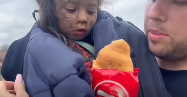 un politist tine o fata in brate si ii da sa manance un corn