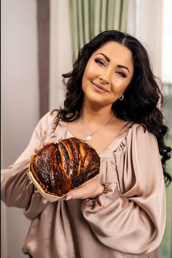 gabriela cristea cu parul ondulat imbracata in bluza roz tine un cozonac in mana