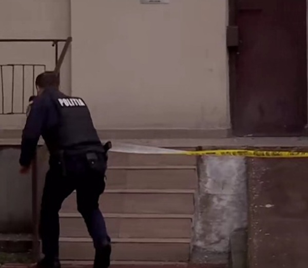 un politist la scara unui bloc pune banda galbena nu treceti