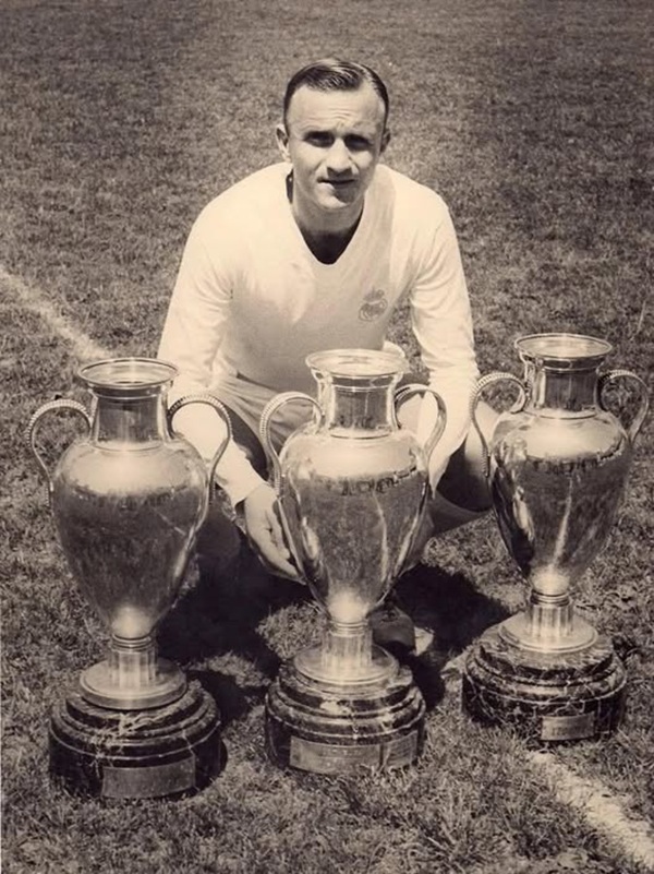 jucator de fotbal pe teren langa 4 cupe importante