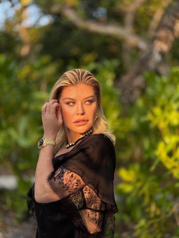 loredana groza imbracata in negru isi trece mana prin par in natura