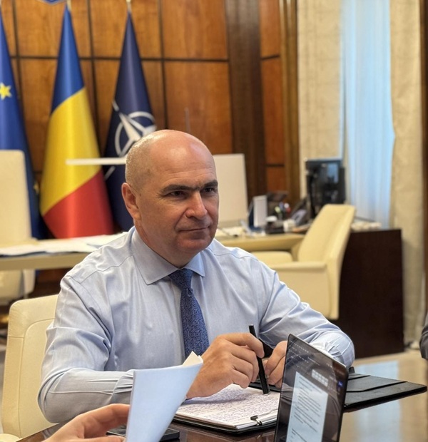 ilie bolojan cu camasa bleu si cravata sta la masa discutiilor