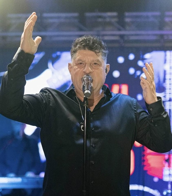 tavi colen cu mainile in aer in camasa neagra canta la microfon