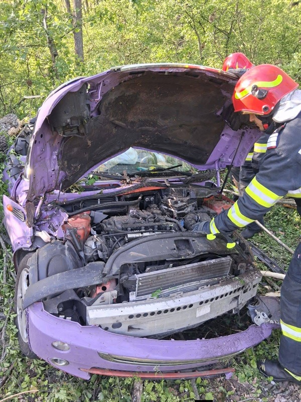 pompier se uita sub capota unei masini implicata in accident