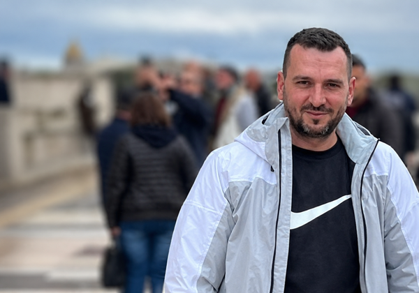 barbat in tricou negru si geaca alba intr-un oras in multime