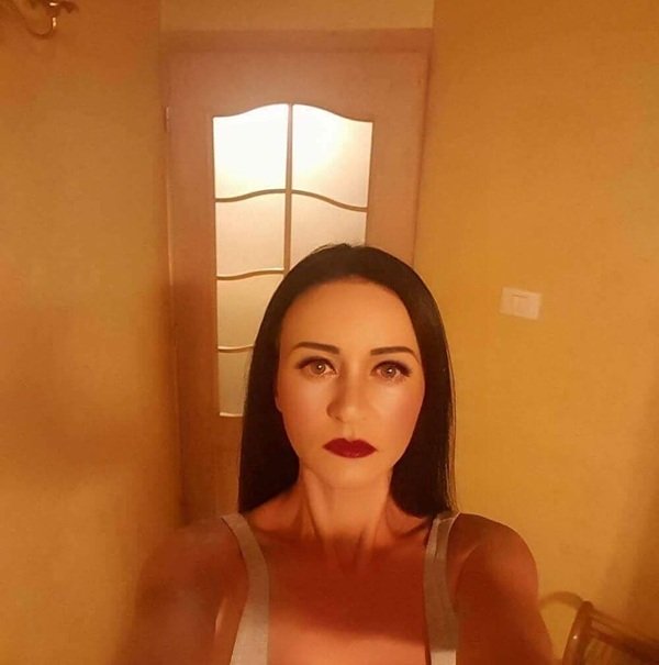 portret de femeie bruneta cu buzele rosii in maieu alb in casa