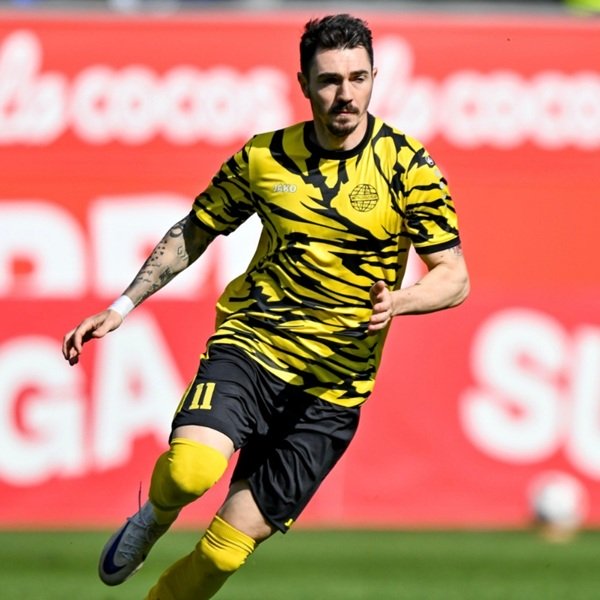 dragos huiban imbracat in negru si galben pe terenul de fotbal loveste mingea
