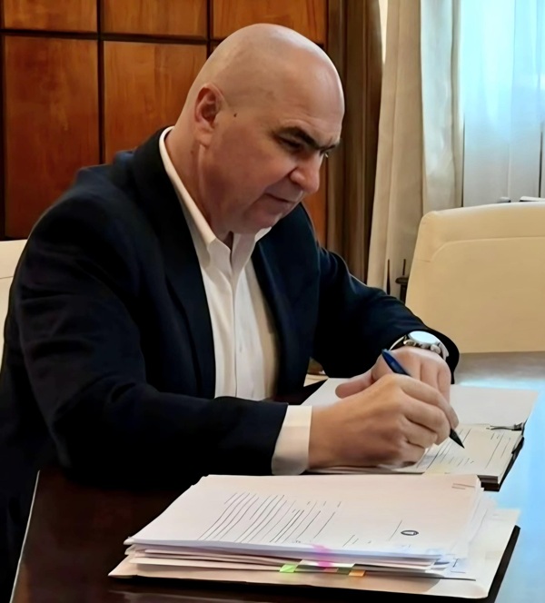ilie bolojan in costum negru si camasa alba semneaza acte