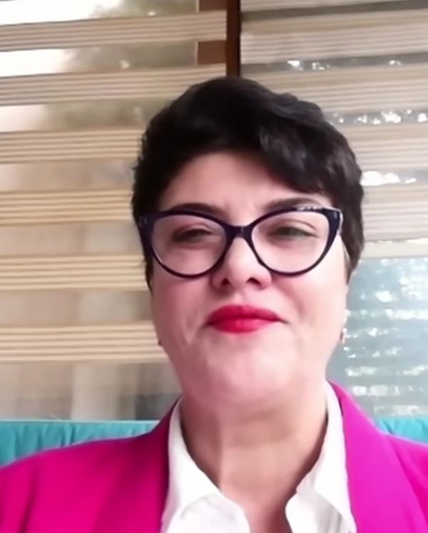 femeie tunsa scurt cu camasa alba buze rosii si cravata rosie cu sacou roz