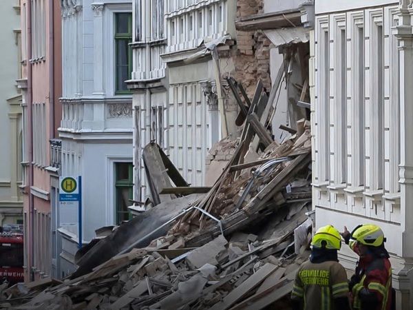 doi muncitori privesc la o cladire afectata de explozie daramaturi