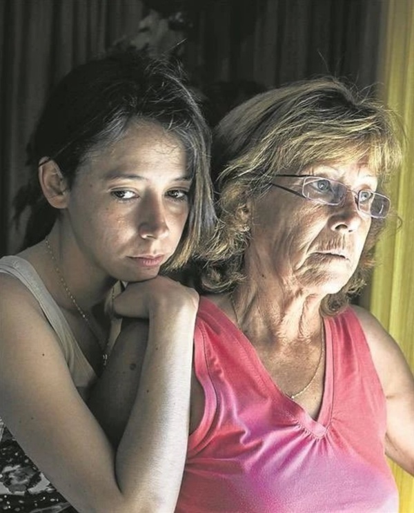 o femeie tanara cu parul prins se sprijina pe umarul unei femei mature blonda