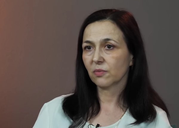 femeie cu parul saten mediu imbracata in alb da un interviu